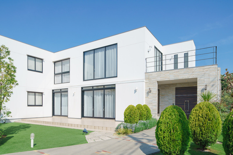 緑に囲まれた大きな白い一戸建て